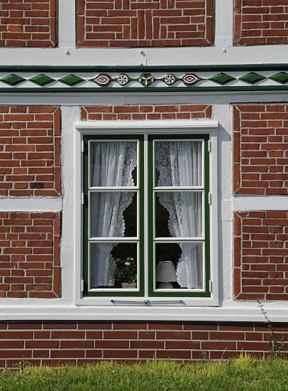 Fotografie Fenster + Schnitzerei Fachwerkhaus  11_21631 Holzfenster in einem Fachwerkhaus; die Gardinen sind mit Spitzen versehen. Der Balken ber dem Fenster ist mit farbig abgesetzten Schnitzereien versehen.  www.hamburg-bilder.org